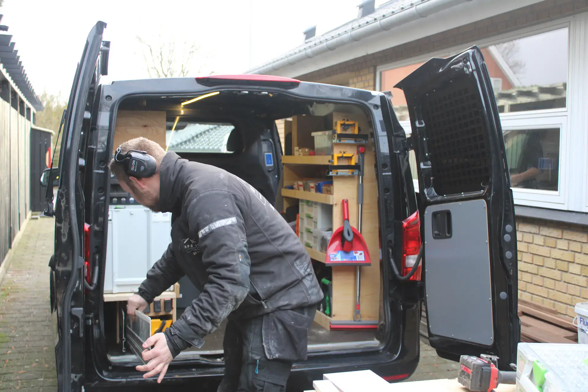 Mand arbejder i en varevogn med værktøj og opbevaringsskabe.